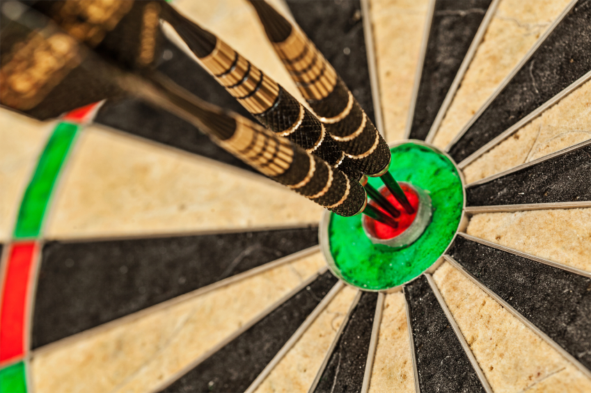 Success hitting target aim goal achievement concept background - three darts in bull's eye close up